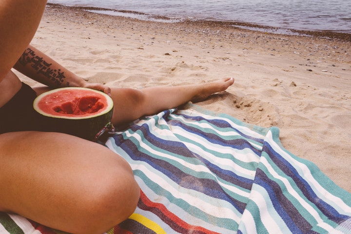 Kvinna äter melon på stranden